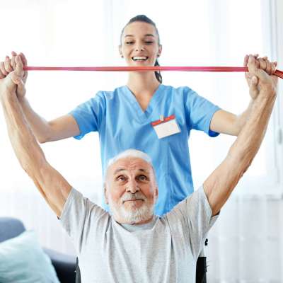 Doctor or nurse caregiver exercise with senior man at home or nursing home